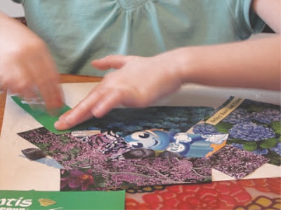 child gluing clippings on construction paper