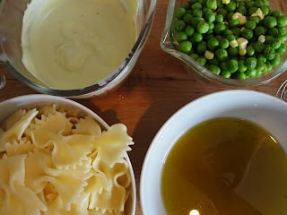 four bowls of bow tie pasta, creamy dressing, oil dressing and peas