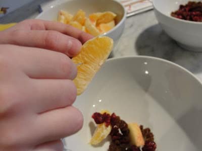 poking an orange slice with a toothpick to make garland