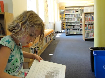 kid reading books at library