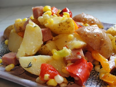 warm potato salad with corn, roasted veg and sausage on a plate