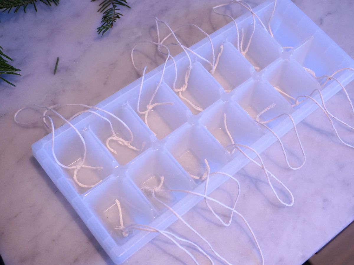 empty ice cube tray with loops of string inside each cell