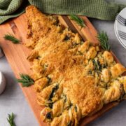 baked spinach dip filled christmas tree appetizer on wooden board with plates