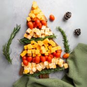 christmas tree cheese platter surrounded by rosemary sprigs and a green tea towel