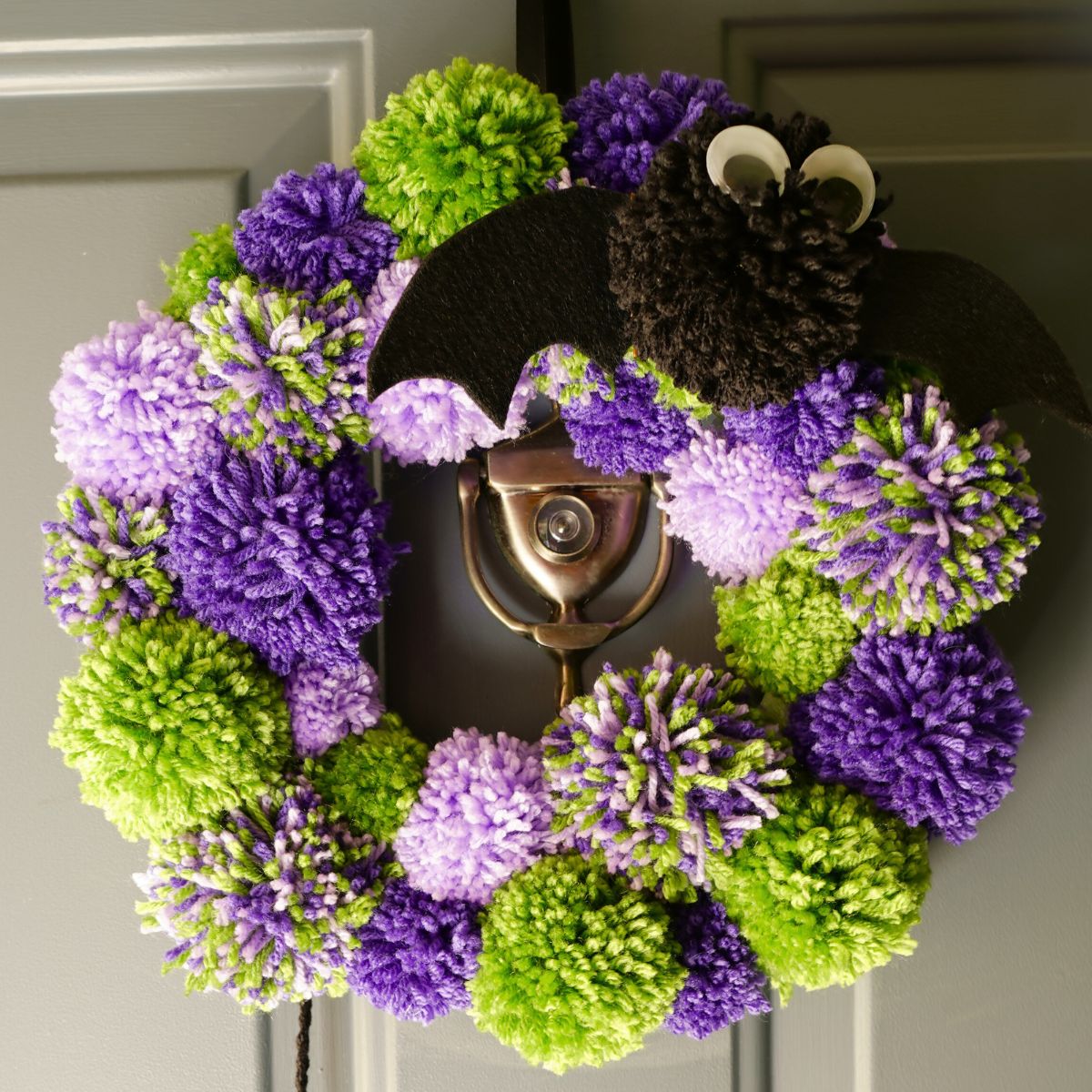 halloween pom pom wreath close up hanging on door featured image