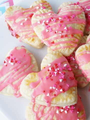 close up of strawberry jam filled heart-shaped pop tarts on a plate