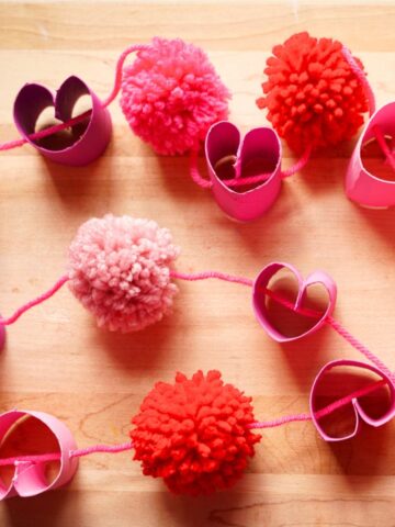 close up of toilet paper roll heart and pom pom garland