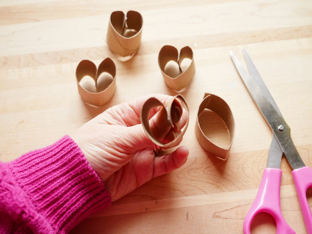 fingers pressing together toilet roll heart with pair of scissors