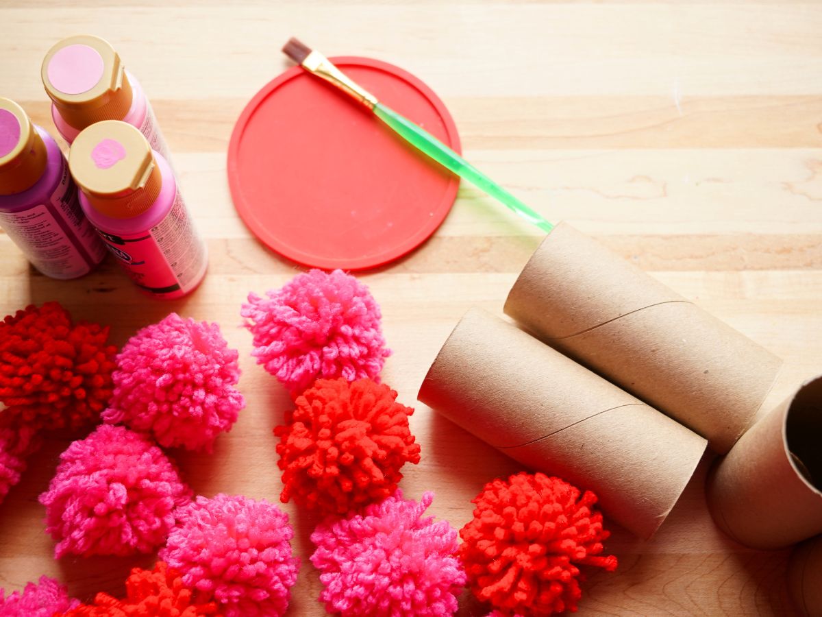 supplies for making toilet paper roll heart garland - pom poms, toilet paper rolls, paints and paintbrush