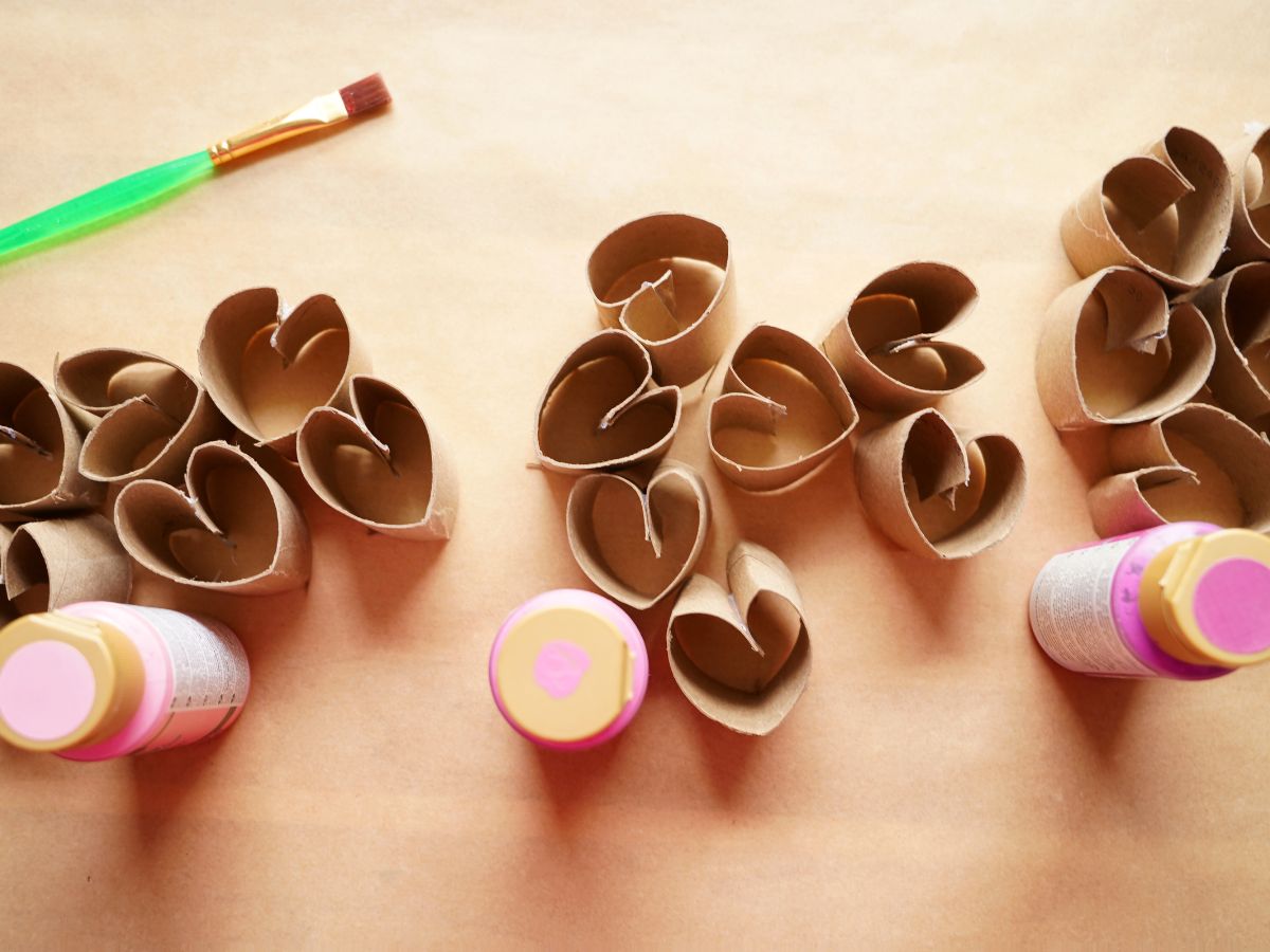 toilet roll hearts sorted into three piles with three pink paints and a paintbrush