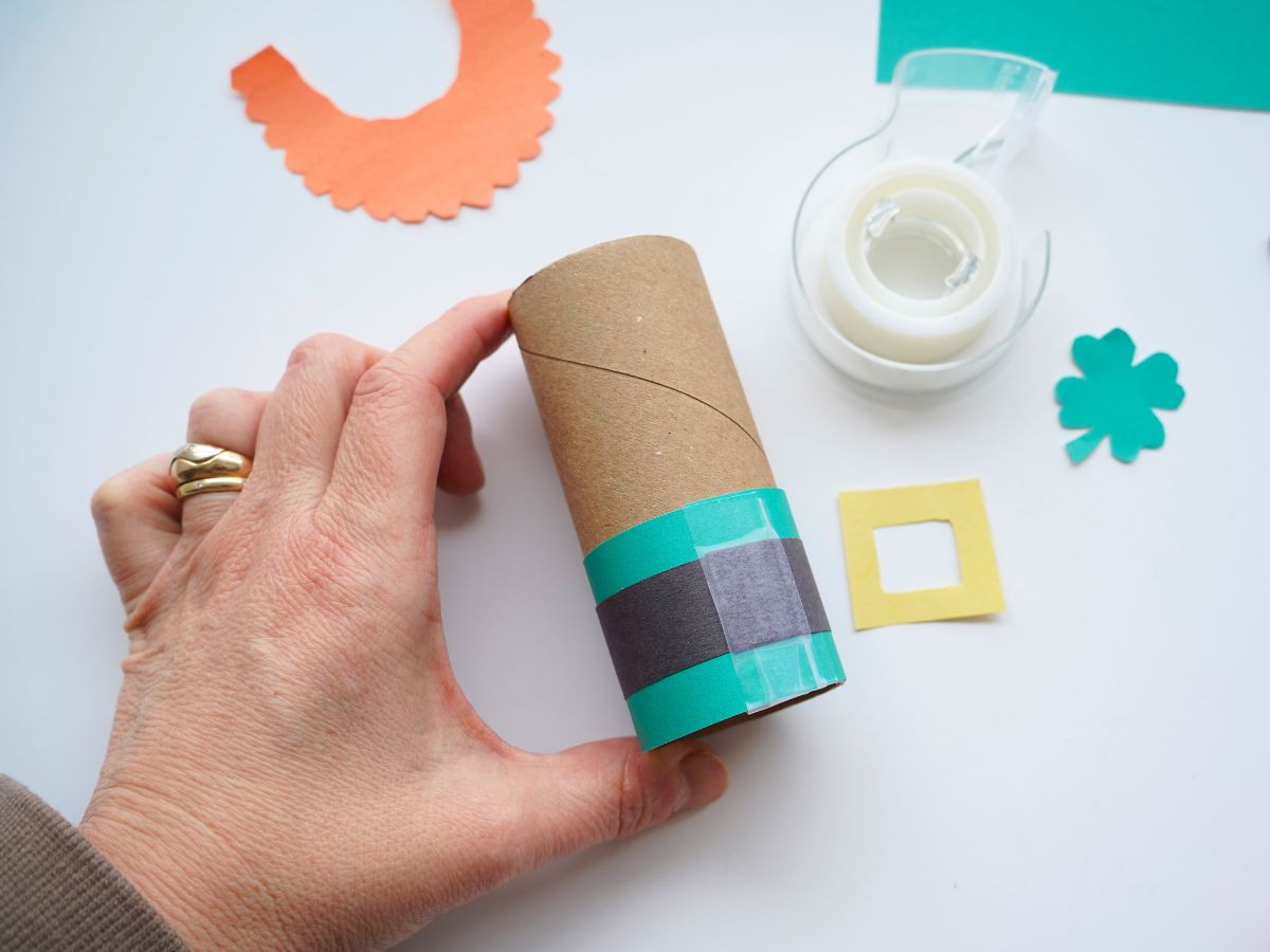 hand holding toilet paper roll with leprechaun suit taped on